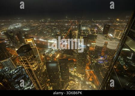 Ein atemberaubender nächtlicher Blick auf Abu Dhabi City von einem der höchsten Türme aus mit glitzernden Wolkenkratzern, beleuchteten Straßen und Reflexionen Stockfoto