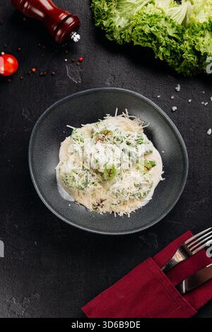Brokkoli in cremiger Parmesan-Sauce auf dunklem Teller, über dem Kopf, Restaurant-Stil Stockfoto