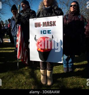 Burlington, Massachusetts, USA. November 2025. 31. Wöchentliche Anti-EIS-Demonstration „Bearing Witness“ vor dem New England Field Office of Immigration and Customs Enforcement (ICE), 26 km nordwestlich von Boston, MA. Die wöchentliche friedliche Demonstration ist von einem jungen Paar im April 2025 auf Hunderte gewachsen, die jeden Mittwoch mittags zwei Stunden vor der Einrichtung stehen. Demonstrant mit selbstgemachtem Schild mit Teufelsgesicht und Maske gegenüber der Einrichtung. Quelle: Chuck Nacke / Alamy Live News Stockfoto