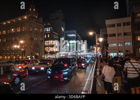 Nachtverkehr und Menschenmassen auf einer breiten Straße im Zentrum von Kyoto, Japan Stockfoto