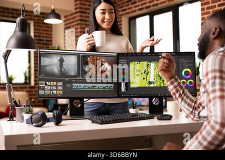 Ein vielseitiges kreatives Paar diskutiert Aufnahmen und genießt Teamarbeit im gemütlichen Heimstudio. Asiatische Frau und afroamerikanischer Mann arbeiten an Postproduktionsfilmen mit Kreativität und Fokus zusammen. Stockfoto