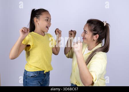 Mutter und Tochter lächeln und heben ihre Fäuste in die Luft Stockfoto