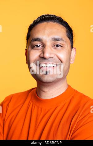 Porträt einer optimistischen indianerin, die ein farbenfrohes Outfit mit positivem Gesichtsausdruck trägt, zufrieden und sorglos aussieht. Ruhiger junger Mann in lässiger Kleidung, zufrieden im Studio. Stockfoto