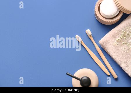 Bambuszahnbürsten mit Wattepads und Handtuch auf blauem Hintergrund Stockfoto