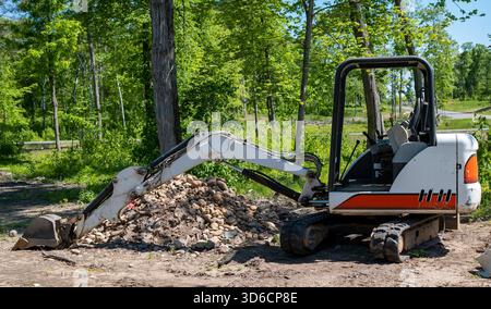 Ein Minibagger auf Schmutz in der Nähe eines Steinhaufens auf einem neuen Bauplatz. Stockfoto