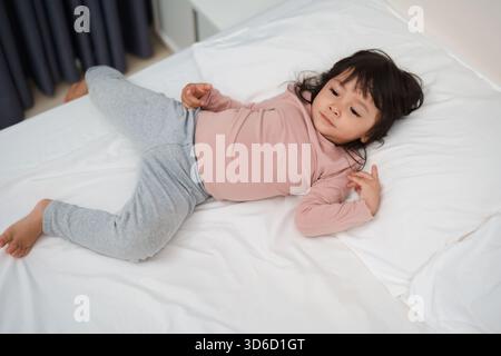 Ein kleines Mädchen, das auf einem Bett liegt Stockfoto