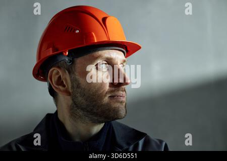 Kaukasischer Mann Mittleren Alters, Der Einen Harten Hut Trägt, Der Wegschaut Und Nachdenkt Stockfoto