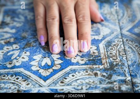 Weiches natürliches Licht hebt die detailreiche Maniküre auf strukturiertem Material hervor Stockfoto