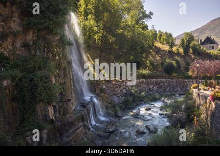 Das Wasser fließt sanft über den Tredos Wasserfall, eingebettet in üppiges Grün und Sonnenlicht in Vall d'Aran, Katalonien Stockfoto
