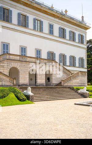 Die elegante Villa Melzi liegt majestätisch am Comer See, mit neoklassizistischer Architektur und wunderschönen Gärten, ideal für gemütliche Spaziergänge unter klarem Himmel. Stockfoto