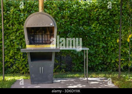 Pizzaofen im Freien und Grillgrill mit Kamin, rustikales Design zum Kochen und Grillen in einer Gartenumgebung. Traditioneller italienischer Outdoor-Kitc Stockfoto