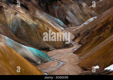 Blick auf die sich windenden Bäche, die sich durch die bunten Rhyolithberge schlängeln, ein Wandteppich aus Ocker, Türkis und Creme, in Landmannalaugar, Rangarbing Stockfoto