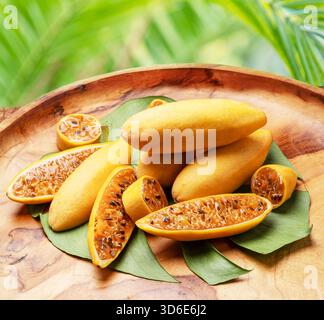 Curubas oder Bananen Passionsfrüchte und Scheiben auf Holzteller, grüner Natur Hintergrund. Stockfoto