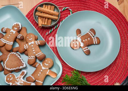 Lebkuchenmänner, weihnachtskekse dekoriert mit königlicher Glasur auf blauem Teller, Blick von oben. Stockfoto