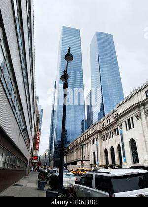 New York, USA - 19. November 2023: Geschäftige New Yorker Straßenszene mit Glashochhäusern in Manhattan West, einer hohen Straßenlaterne und gelben Taxis. Stockfoto