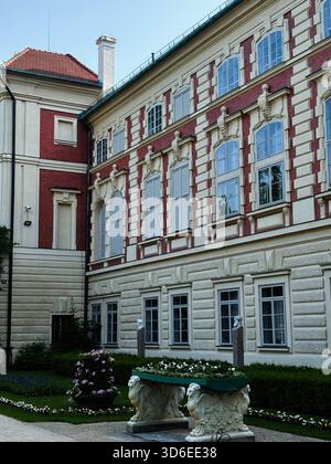 Lancut, Polen - 19. Juli 2025: Sonnendurchfluteter polnischer Innenhof der Burg Łańcut mit einer verzierten roten Ziegelfassade, cremefarbenen Steinen und klassischen Statuen. Stockfoto