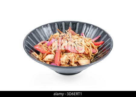 Wok-Nudeln mit Huhn, Pfeffer, Zwiebeln, Karotten und Sesamsamen in einer schwarzen Schüssel serviert Stockfoto