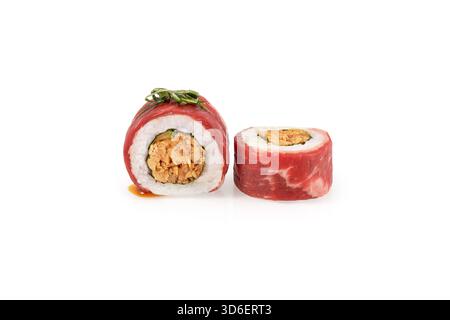 Zwei Uamaki-Sushi-Brötchen, einer in zwei Hälften geschnitten, mit der scharfen Füllung und der dünnen Rindfleischverpackung, isoliert auf weiß Stockfoto