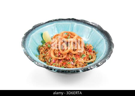 Serviert mit köstlichem gebratenem Reis mit Calamari, Gemüse und knusprigen Zwiebelringen, garniert mit einem Limettenkeil und frischen Kräutern Stockfoto