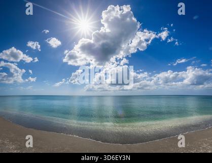 Blauer Himmel weiße Wolken und Sonne über dem ruhigen Golf von Amerika formell der Golf von Mexiko vom Strand in Venedig Florida USA Stockfoto