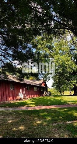Eine ruhige Farm-Szene im Süden von Illinois mit einer roten Scheune, Schaukel und üppigen Schatten. Stockfoto