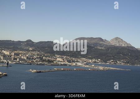 Weite Küstenlandschaft mit Ceuta, Hafeninfrastruktur und bergigem Gelände dahinter. Stockfoto