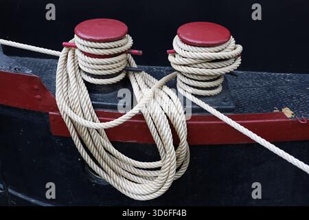Rote und schwarze Metallanker mit Seilen, die am Ankerboot befestigt sind Stockfoto