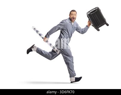 Langer Schuss eines Mannes im Pyjama, der mit Koffer und Sonnenschirm auf weißem Hintergrund läuft Stockfoto