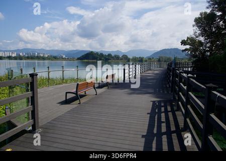 Eine Aussichtsplattform mit Bänken erstreckt sich von der Promenade am Uiam Lake und blickt auf entfernte Wohnungstürme und Berge über das Wasser entlang Chuncheo Stockfoto