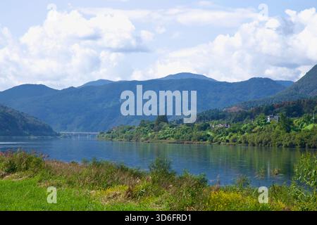 Sanftes Nachmittagslicht fällt über den Bukhangang, während bewaldete Hügel in Richtung Chuncheon aufsteigen, mit verstreuten Häusern über Schilf und seichten Flüssen. Stockfoto