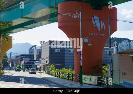Ein Blick auf die orange Jarasum-Säule unter dem Viadukt der Gyeongchun-Linie zeigt das Logo und den Slogan der Insel neben Straßenlaternen, Drähten und Mixed-u Stockfoto
