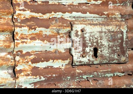 Abblätternde Farbe und rostiges Metall mit Schlüsselloch Stockfoto