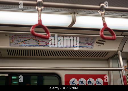 Ein U-Bahn-Innenraum mit einer Streckenkarte über den Sitzen, mit roten Handläufen sichtbar, U-Bahn-System in Hongkong, China am 24. Juli 2015 Stockfoto