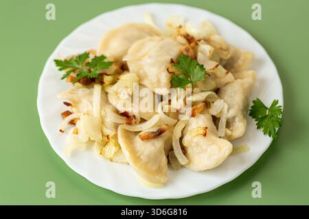 Hausgemachte Teigtaschen mit gebratenen Zwiebeln, serviert auf weißem Teller. Stockfoto
