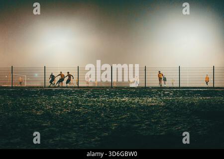 Nachtszene mit Fußballfeldern mit Spielern im Herbst, nebelige Atmosphäre. Stockfoto