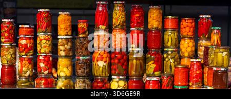 Gemischtes eingelegtes Gemüse in Gläsern an einem Marktstand mit hellen Farben und Glasbehältern Stockfoto