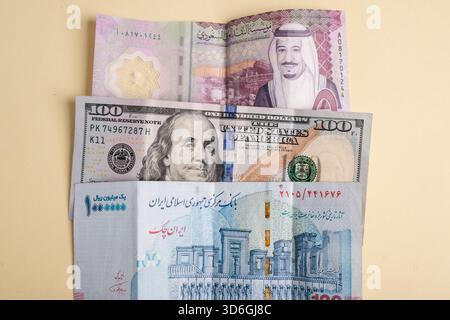 Eine Sammlung von Banknoten aus verschiedenen Ländern, darunter ein Saudi-Rial, ein US-Dollar und ein iranischer Rial, die in mehreren Schichten angeordnet sind Stockfoto