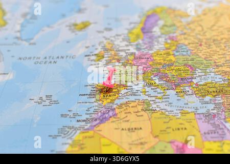 Europakarte mit rosafarbenem Stecknadel in Zentralspanien, die die nahe gelegenen Länder Frankreich, Portugal, Italien, Großbritannien und die umliegenden Meere zeigt. Stockfoto