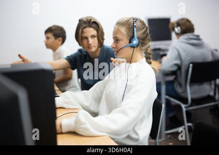 Junge helfen verärgert Mädchen, um Problem auf dem Computer in der Schulklasse zu lösen Stockfoto
