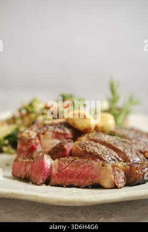 Saftiges gegrilltes Steak mittelselten auf einem weißen Teller, mit zartem rosafarbenem Fleisch sichtbar Stockfoto