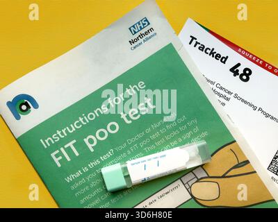 Nahaufnahme eines FIT-Testkits auf einer Informationsbroschüre zur Darmkrebsvorsorge mit sichtbarem Anweisungstext UK NHS Stockfoto