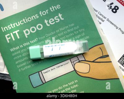 Nahaufnahme eines FIT-Testkits auf einer Informationsbroschüre zur Darmkrebsvorsorge mit sichtbarem Anweisungstext UK NHS Stockfoto