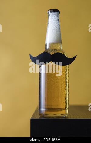 Essen, Flasche Bier mit schwarzem Schnurrbart auf gelbem Hintergrund. Konzept für Party Junggesellen, Movember, Vatertag, 23. februar, Feiertag Stockfoto