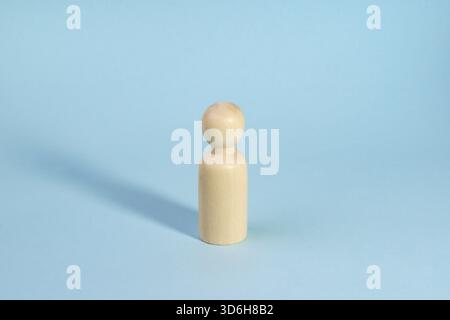 Eine männliche Holzfigur steht allein auf gelbem Hintergrund isoliert. Selbstbewusstes, unabhängiges Konzept für Person, Mentor, Coach, Führungskraft. Vorderansicht Stockfoto