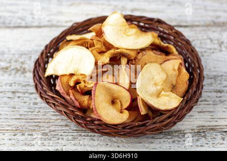 Essen, Ein Haufen getrockneter Äpfel in Korb auf weißem hölzernem Hintergrund. Getrocknete Fruchtchips. Gesundes veganes Essen Stockfoto