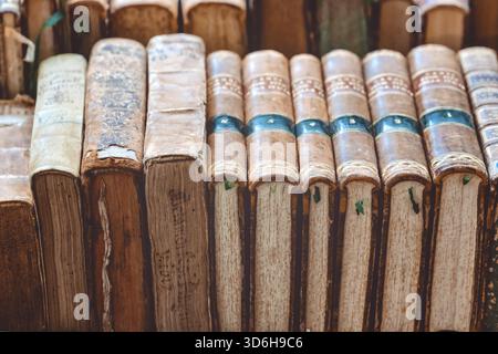 Alte alte Bücher stapeln sich mit braunen Deckeln, die auf einem Regal auf dem europäischen Straßenmarkt liegen. Stapel gebrauchter brauner Bücher. Retro-Literatur-Bücherregal. Antike grun Stockfoto