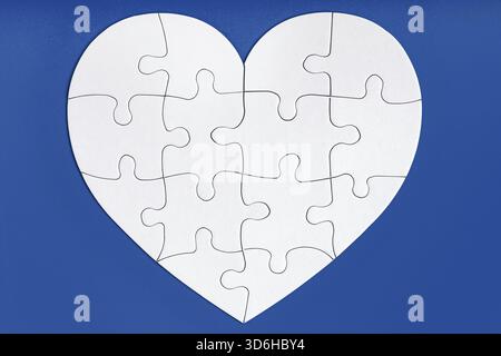 Puzzleteile in Herzform auf blauem Hintergrund. Liebe, Wohltätigkeit, Spende, helfendes Konzept. Perfekte Übereinstimmung, Wiedersehen Stockfoto