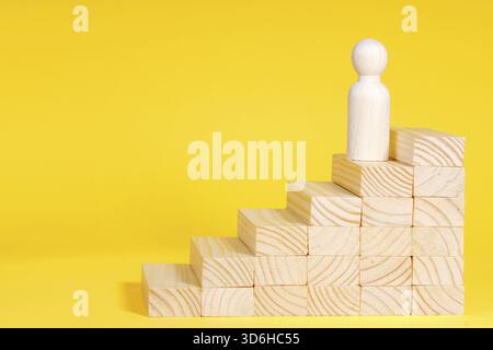 Geschäftsmann, der Treppen klettert. Erfolgsprozess für Unternehmenswachstum, Karriereleiter. Ambitions-Konzept. Holzfigur auf gelbem Hintergrund Stockfoto