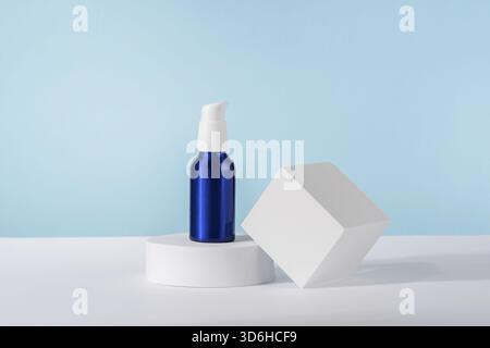 Kosmetische Creme metallische Pumpe Flasche Mockup auf blauem Hintergrund mit stilvollen Requisiten auf weißem geometrischen Podest Podium. Nicht gebrandete Lotion Beauty-Produkt Stockfoto