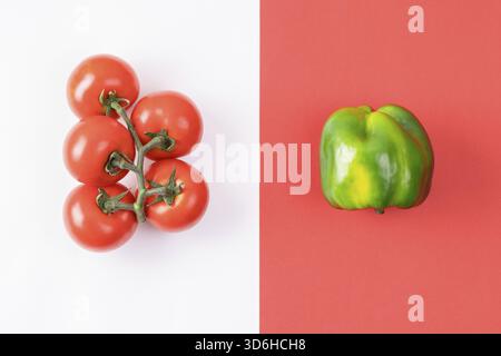 Kreatives Layout aus Pfeffer und Tomaten auf farbenfrohen rot-weißen Hintergrund. Minimales Sommerkonzept. Zutaten für Salat. Gemüsedesign Stockfoto